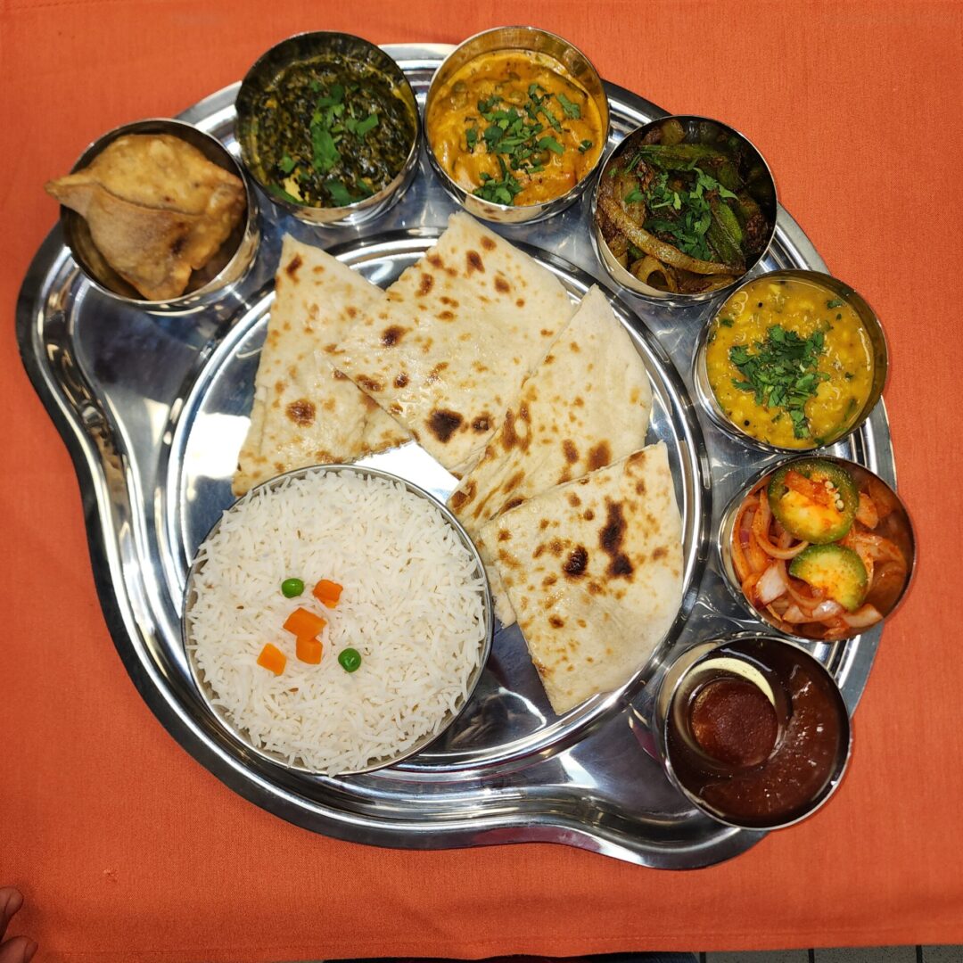 Traditional Indian thali with rice, chapati, and various vegetable dishes.