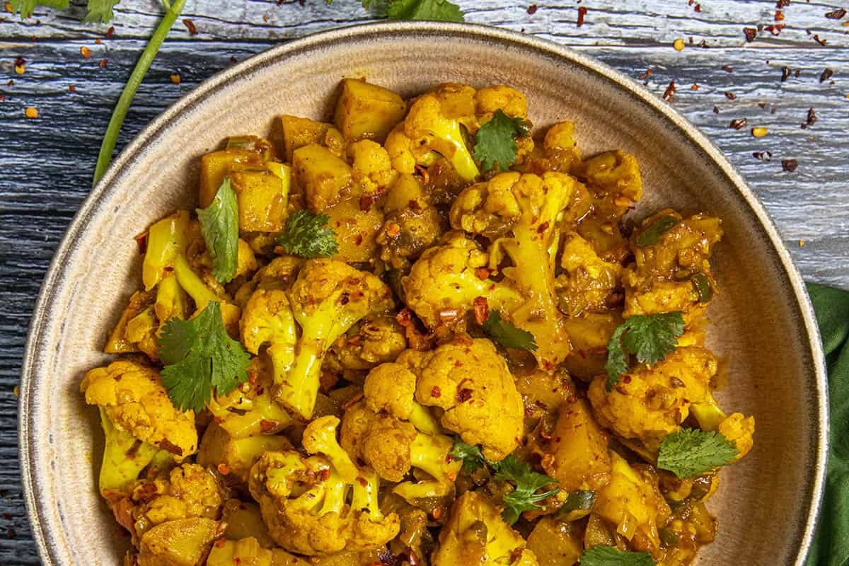 Spiced roasted cauliflower garnished with fresh herbs in a bowl.