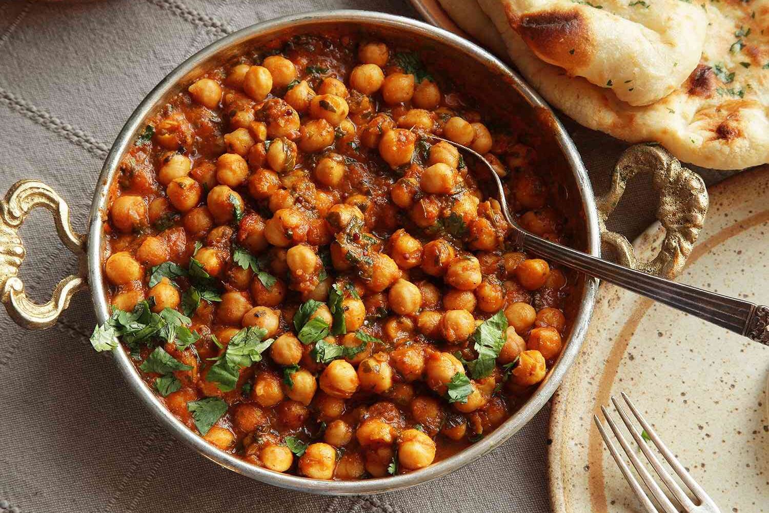 Bowl of roasted chickpeas with herbs and bread on the side.