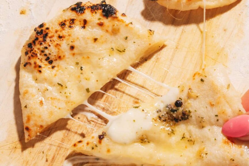 Close-up of a cheesy slice of pizza being pulled away.