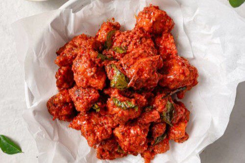 Spicy, crispy fried chicken pieces coated in a vibrant red sauce.