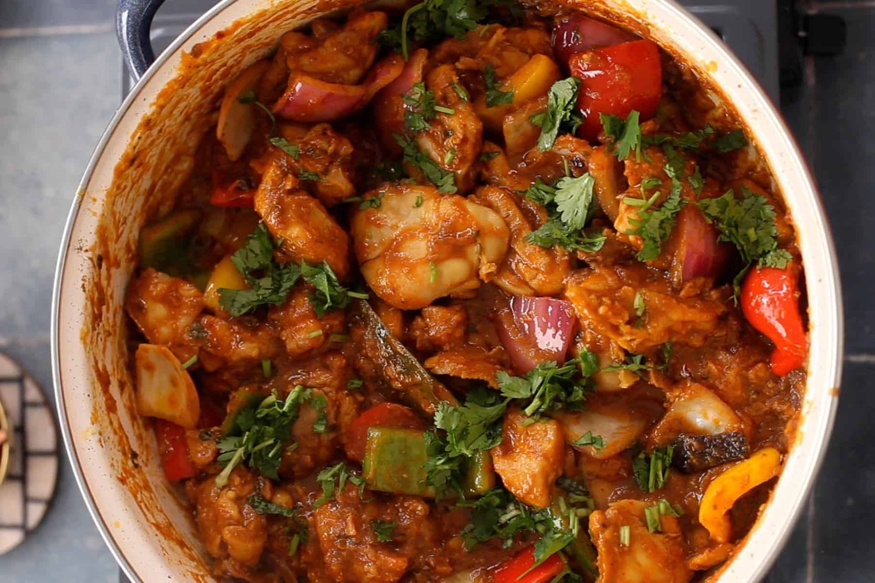 A vibrant shrimp and vegetable curry garnished with fresh herbs.