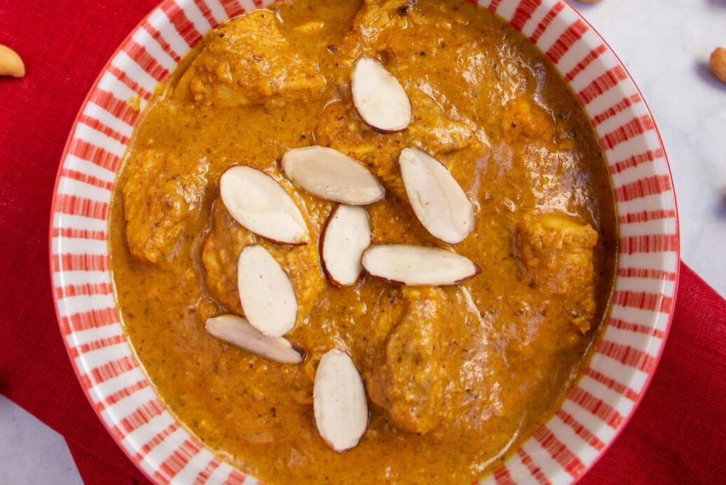 A bowl of creamy curry topped with sliced almonds.
