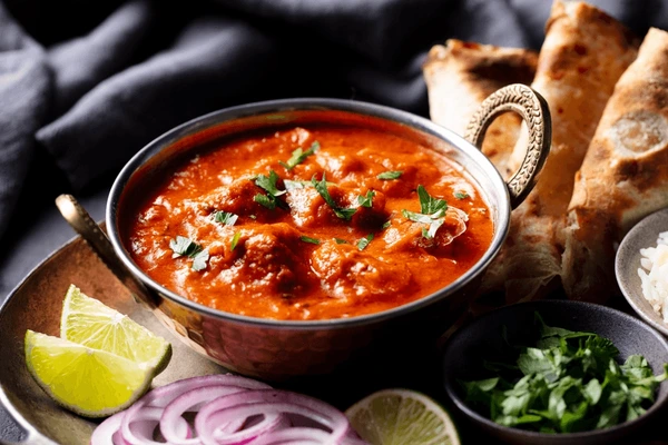 A bowl of spicy Indian curry garnished with fresh cilantro.