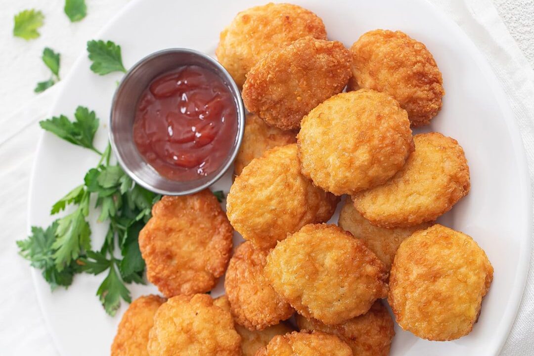 Golden chicken nuggets served with ketchup and parsley garnish.