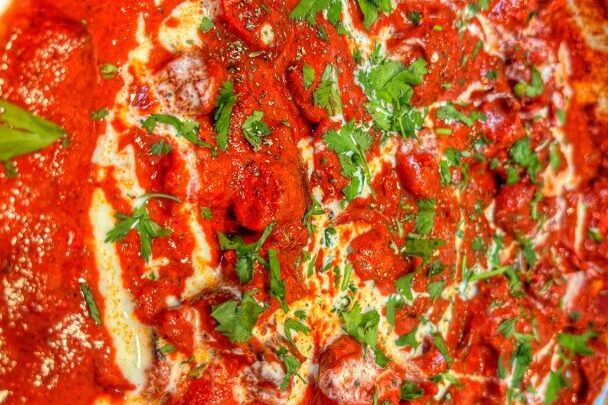 Close-up of a pepperoni pizza with fresh herbs and melted cheese.
