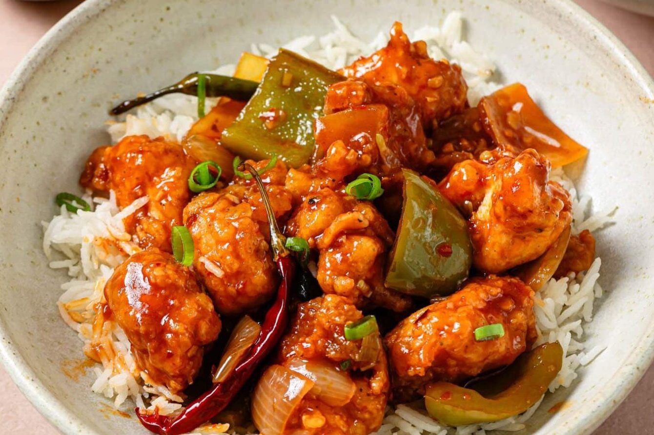 Spicy chicken with peppers and onions on a white plate.