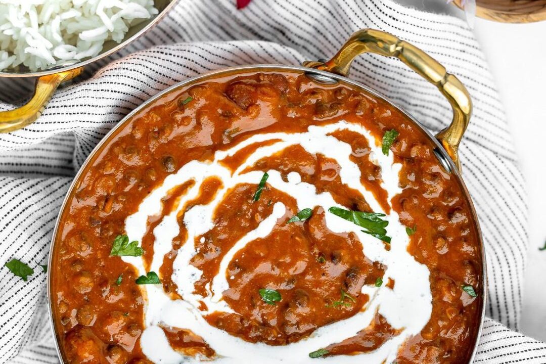 Creamy butter chicken garnished with cilantro and cream swirl.