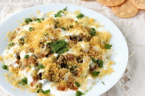 Plate of dahi puri garnished with sev and chutneys.