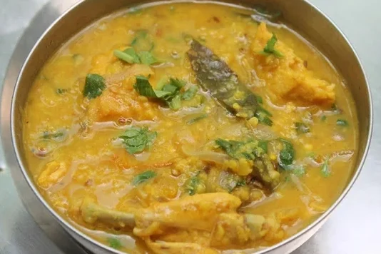Delicious yellow lentil curry garnished with green herbs.