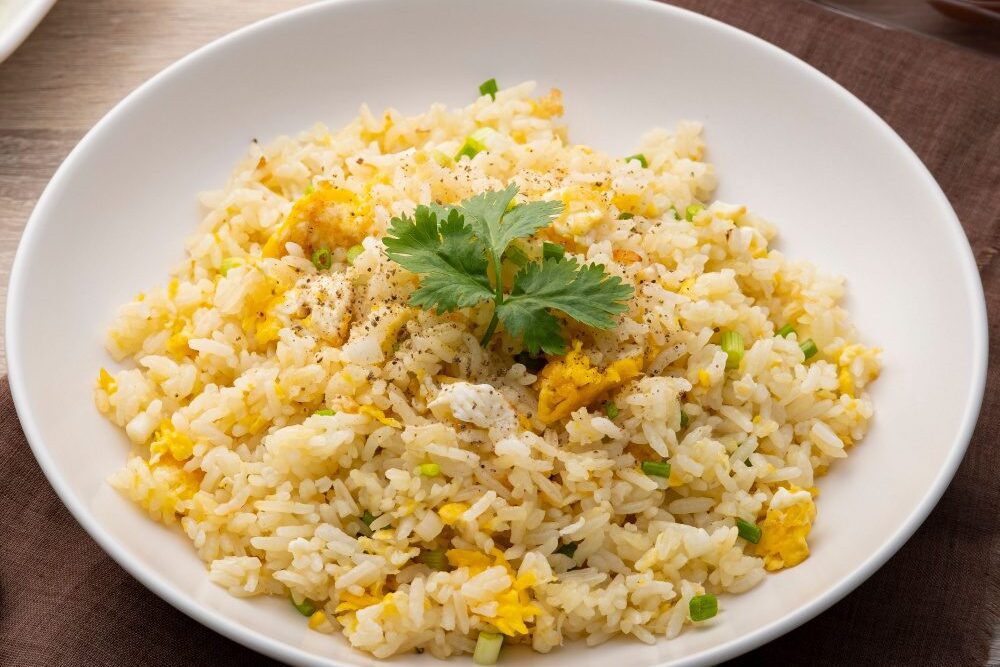 A bowl of egg fried rice garnished with cilantro.