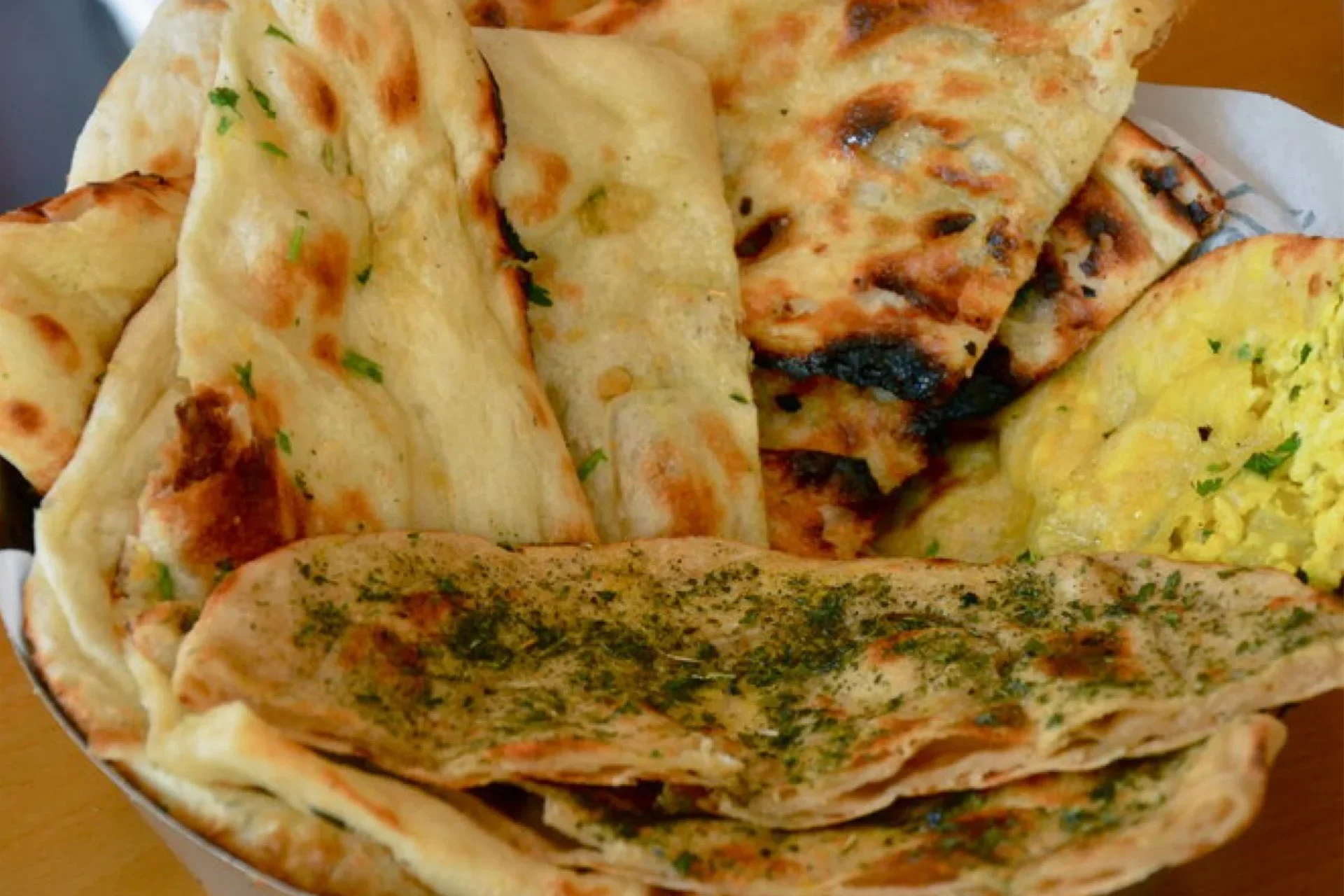 Assorted flatbreads with herbs and toppings.