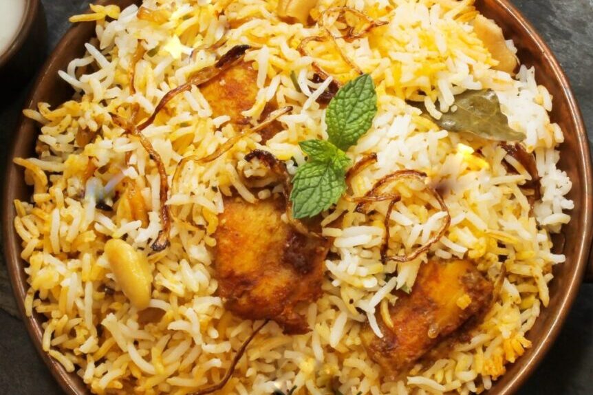 Plate of chicken biryani garnished with mint leaves.