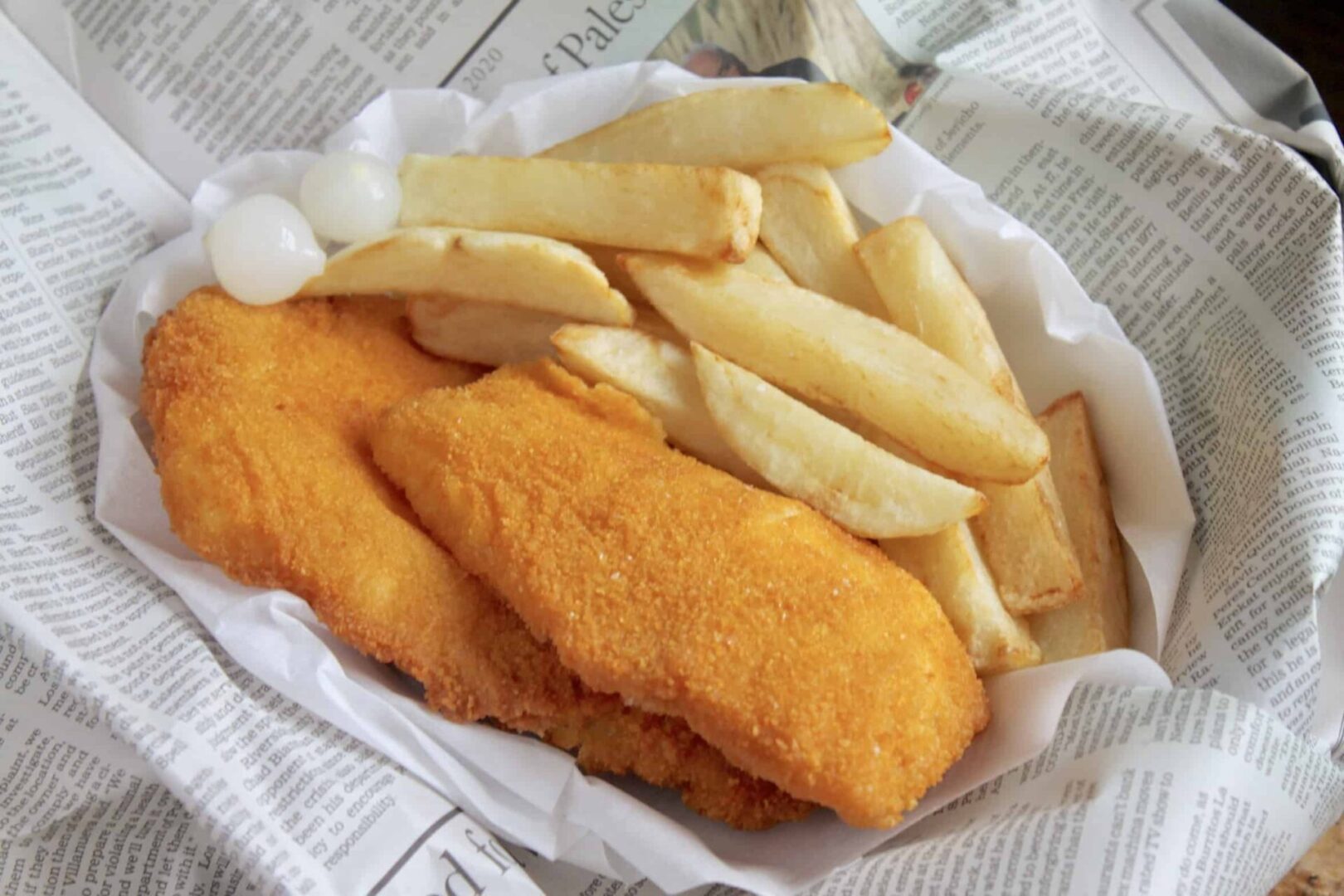Crispy golden fish fillets with thick-cut fries on paper.