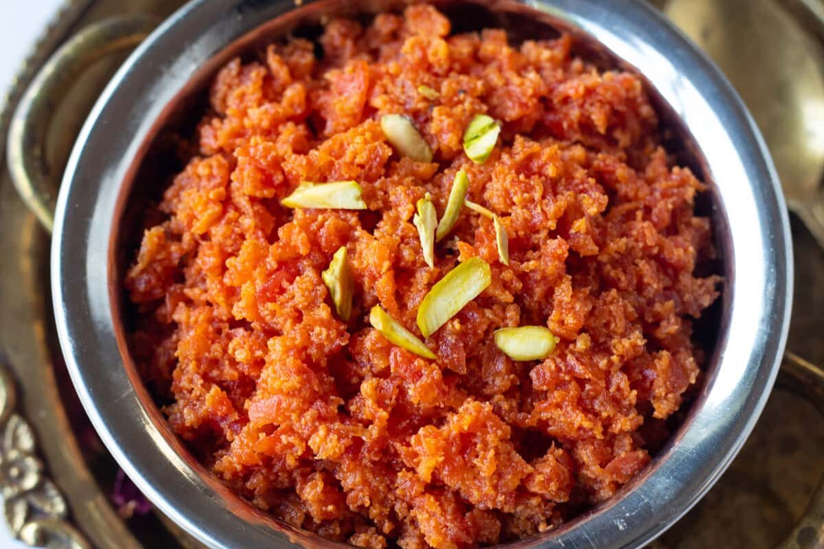 A bowl of vibrant Indian gajar ka halwa garnished with nuts.