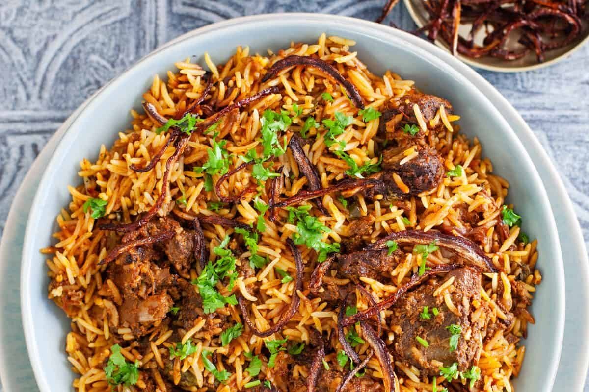 A bowl of flavorful biryani garnished with fresh herbs.
