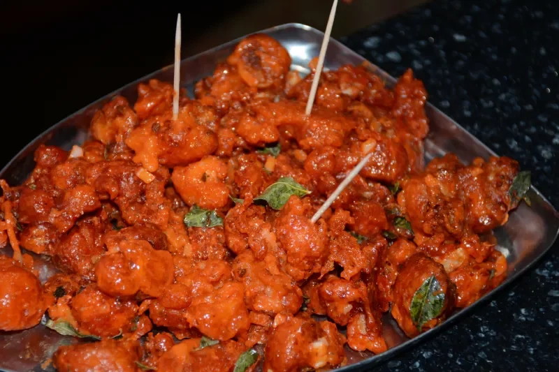 Spicy Indian-style chicken pakoras garnished with coriander and served with toothpicks.