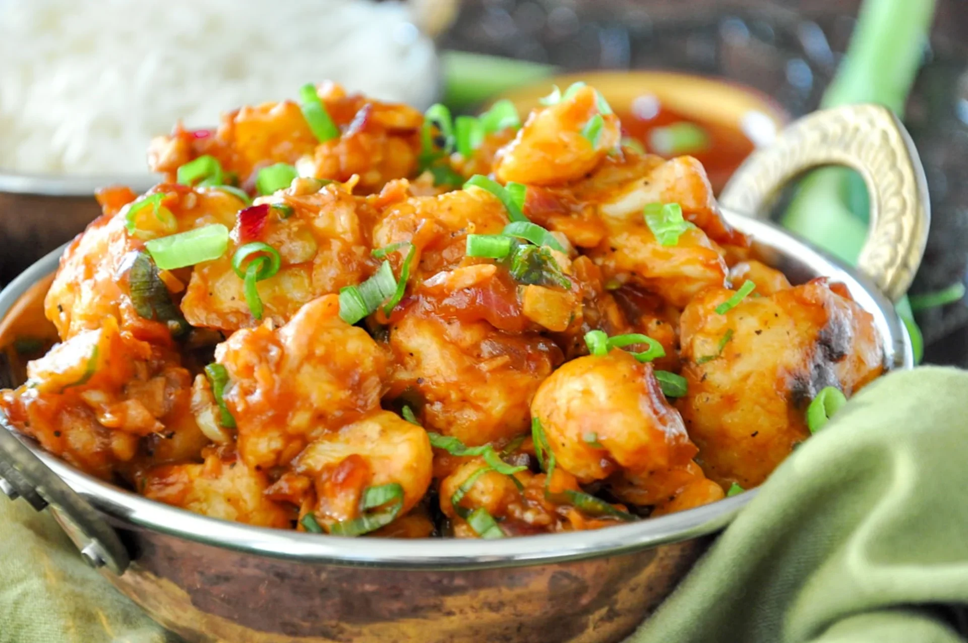 Spicy cauliflower bites garnished with green onions.