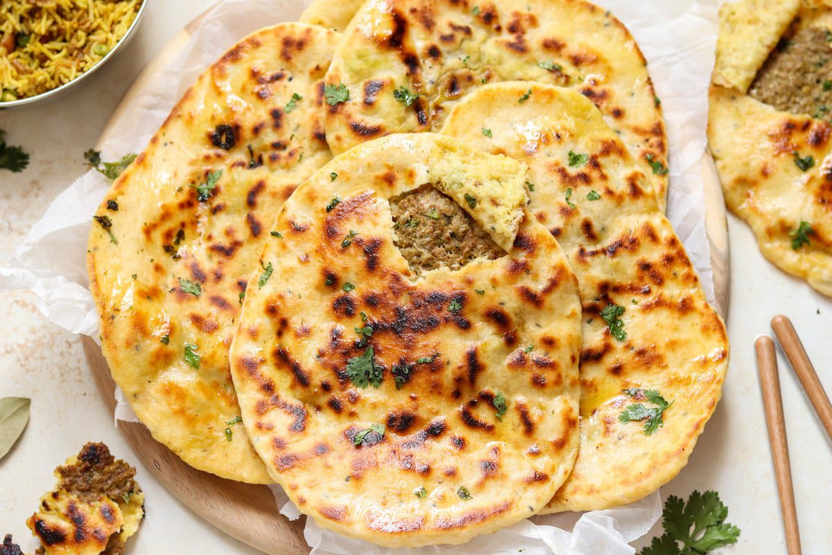 Freshly baked garlic naan bread with herbs and lemon slices.