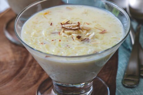 A glass of creamy rice pudding garnished with nuts.