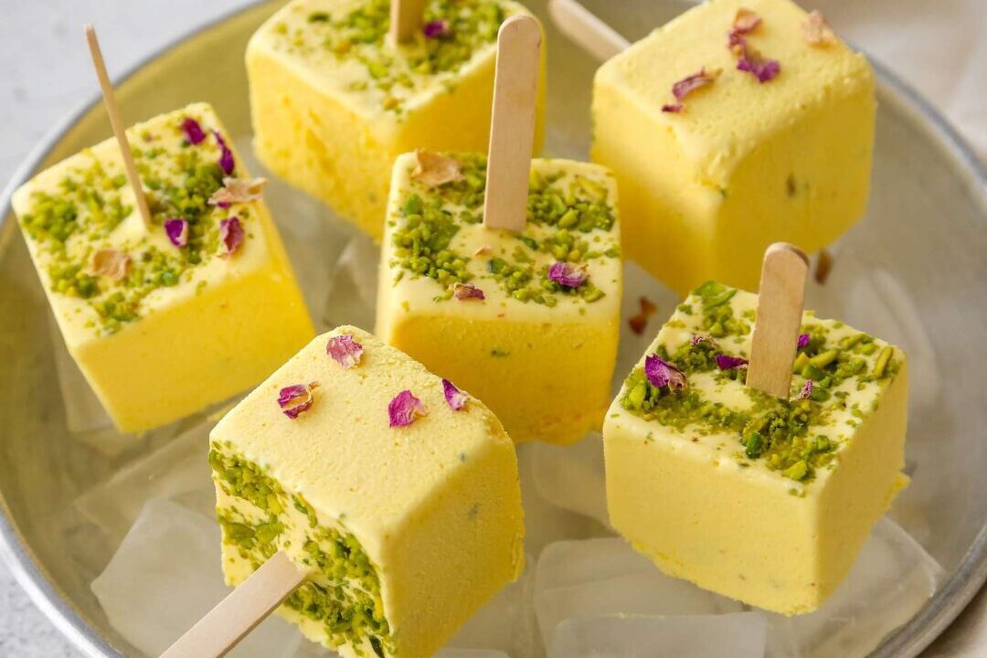 Creamy pistachio and rose popsicles with a smooth yellow coating.