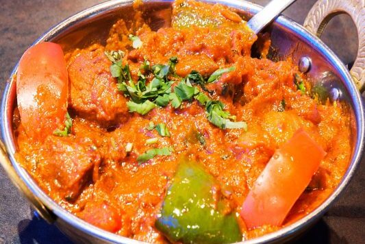 A bowl of rich, creamy tomato-based curry garnished with fresh cilantro.