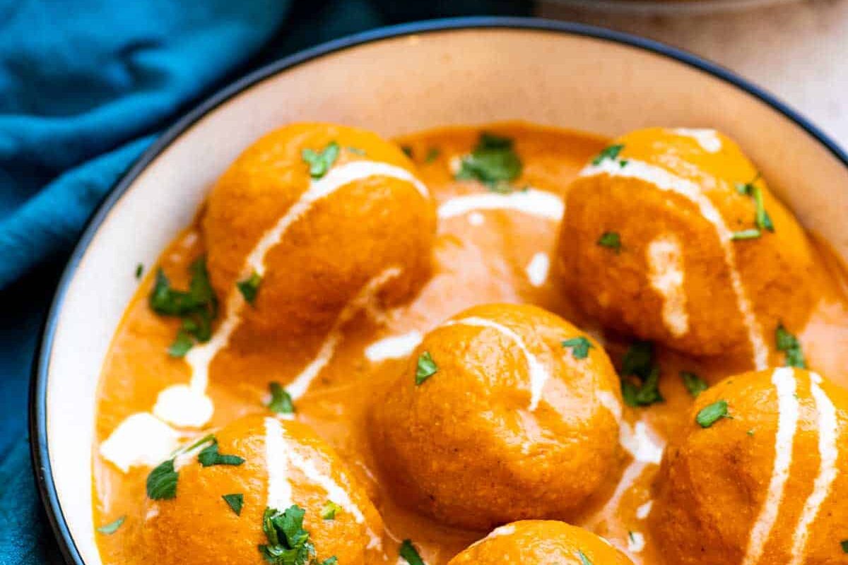 Delicious paneer butter masala garnished with cream and cilantro.