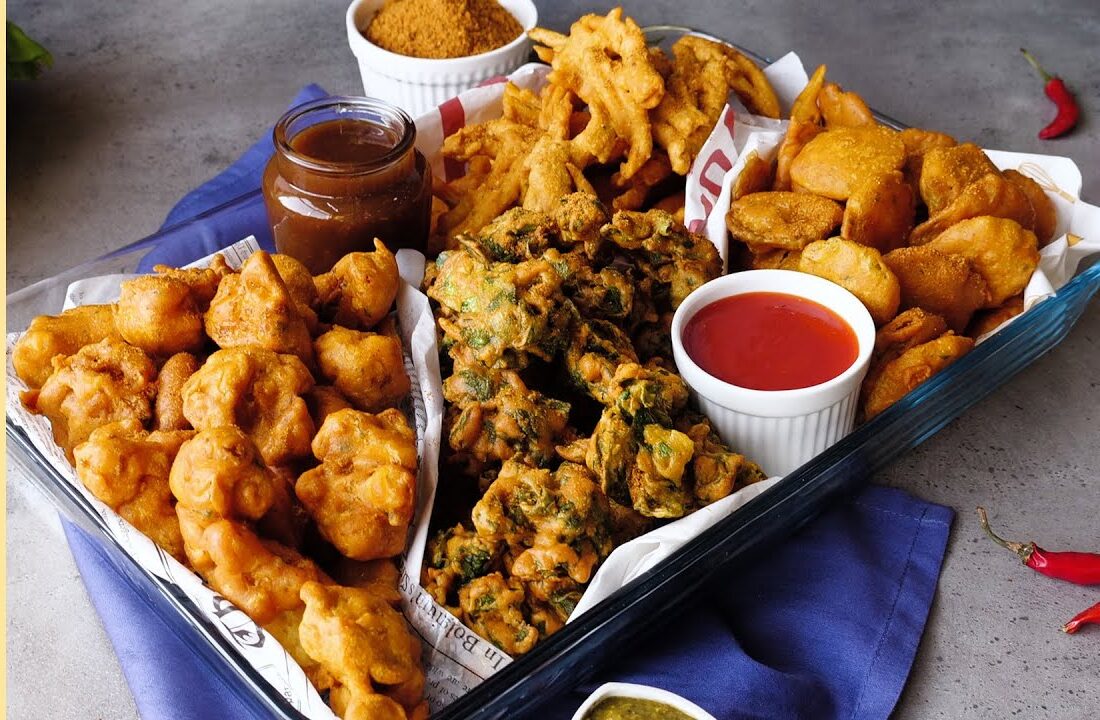A platter of assorted fried snacks with dipping sauces.