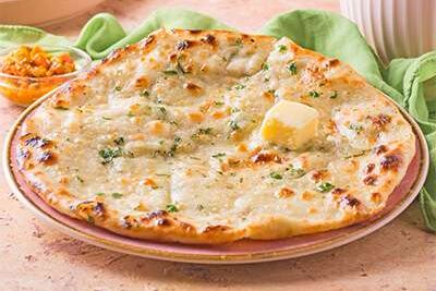 A close-up of a garlic naan bread with butter on top.
