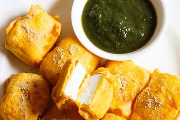 Golden fried paneer pakoras served with green chutney.
