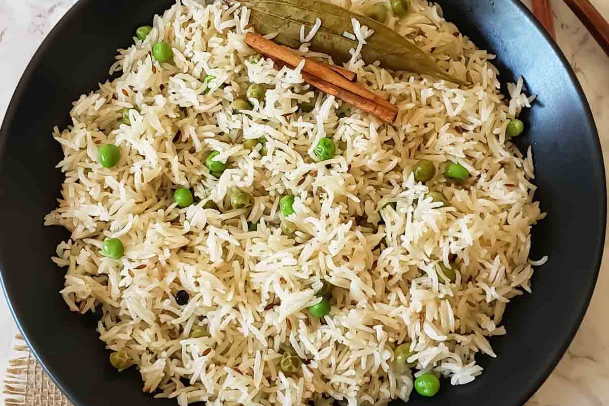 A bowl of fragrant basmati rice with green peas and whole spices.
