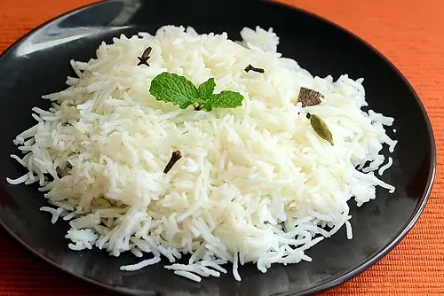 Plate of fluffy white rice garnished with mint leaves.
