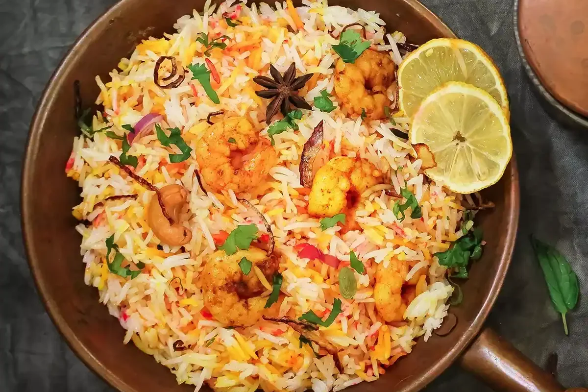 Delicious shrimp biryani garnished with herbs and lemon slices.