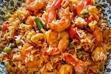 A close-up of shrimp fried rice with vegetables.