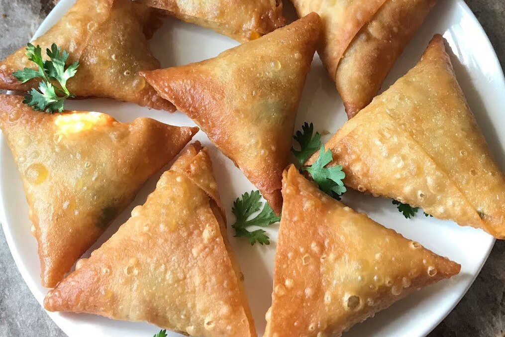 Golden-brown triangular samosas garnished with fresh coriander.