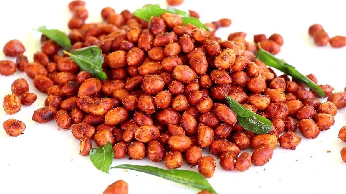 A close-up of spicy roasted peanuts with curry leaves.