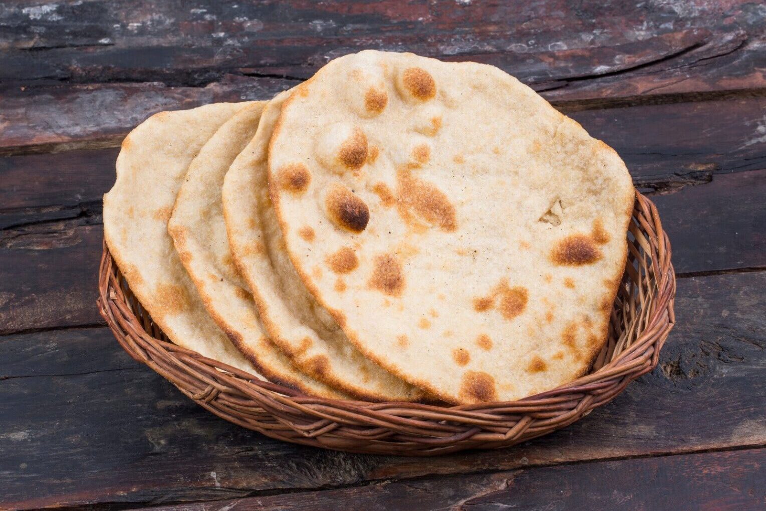 Stack of freshly baked flatbreads in a basket.