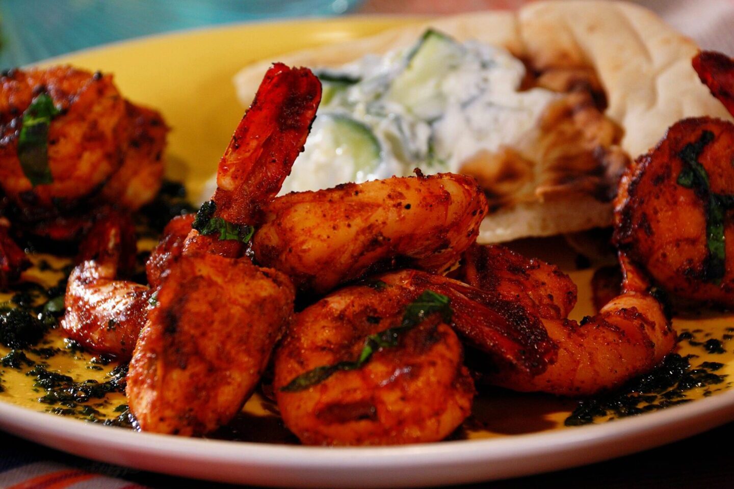 Spicy grilled chicken pieces served with flatbread and cucumber raita.