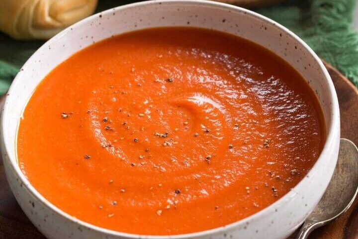 Creamy tomato soup with a swirl of cream in a white bowl.