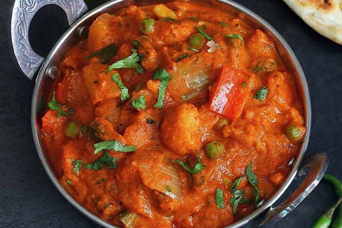 A vibrant bowl of mixed vegetable curry garnished with fresh herbs.