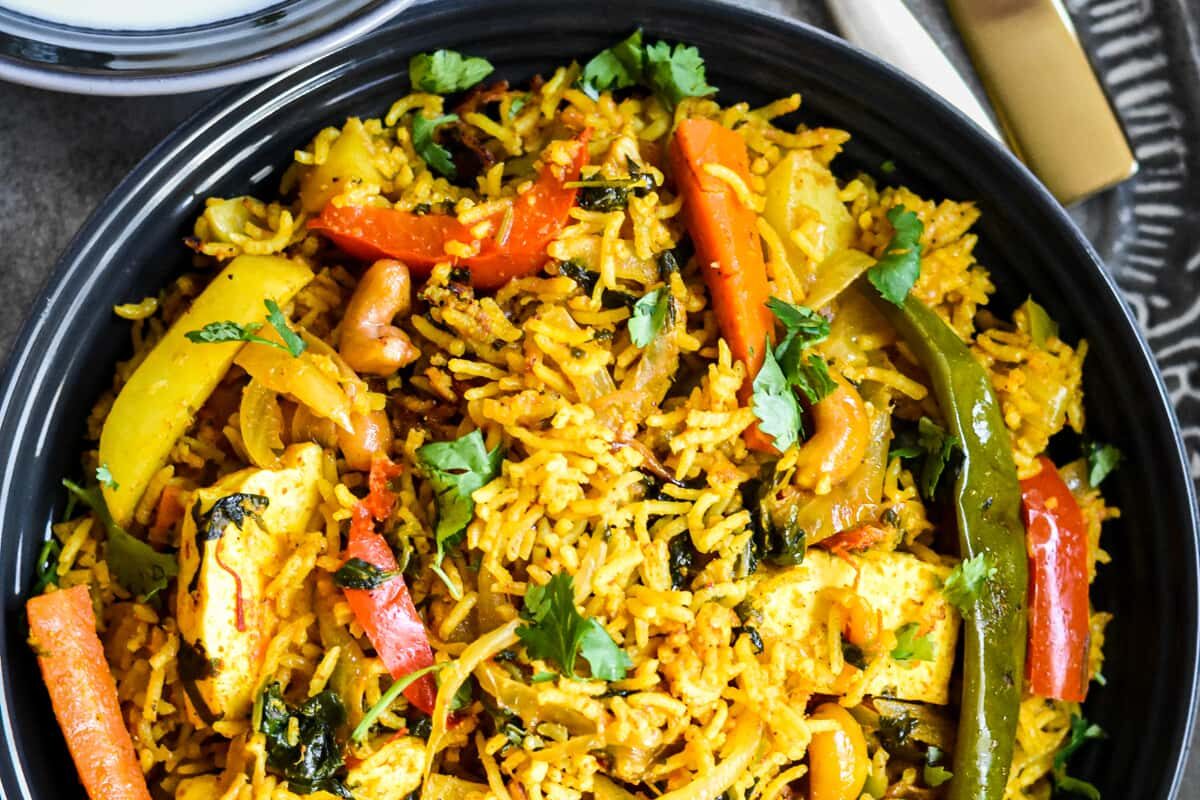 A vibrant plate of vegetable biryani with colorful carrots and spices.