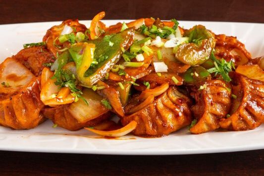 Spicy stir-fried squid with vegetables on a white plate.