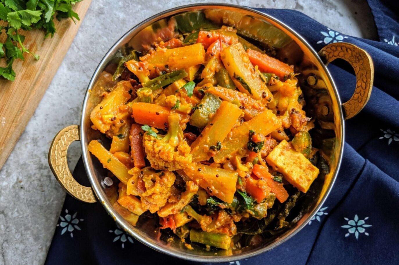 A vibrant vegetable curry with peas and carrots in a steel bowl.