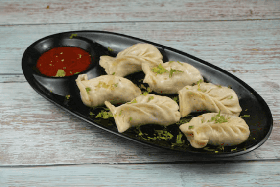 Plate of steamed dumplings with dipping sauce.